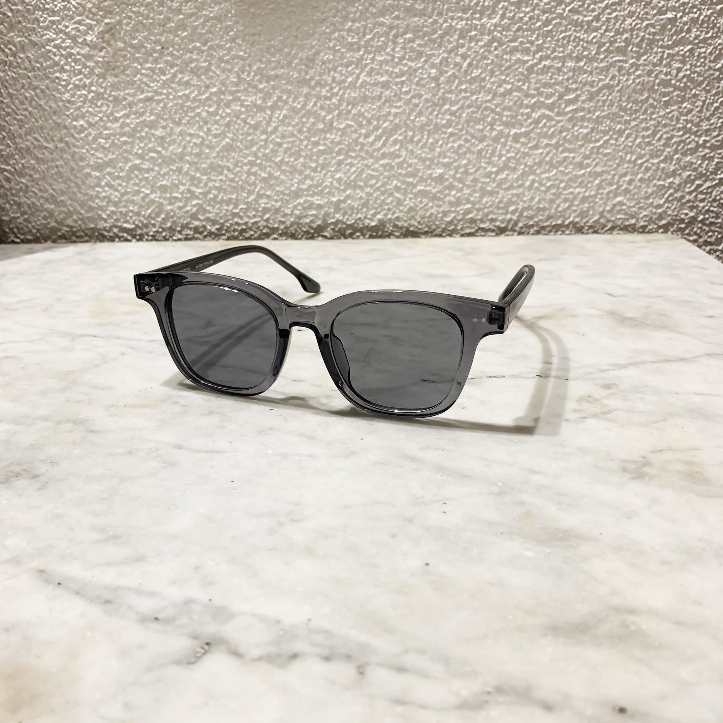 lunettes de soleil pinigoon grises ouvertes sur comptoir en marbre