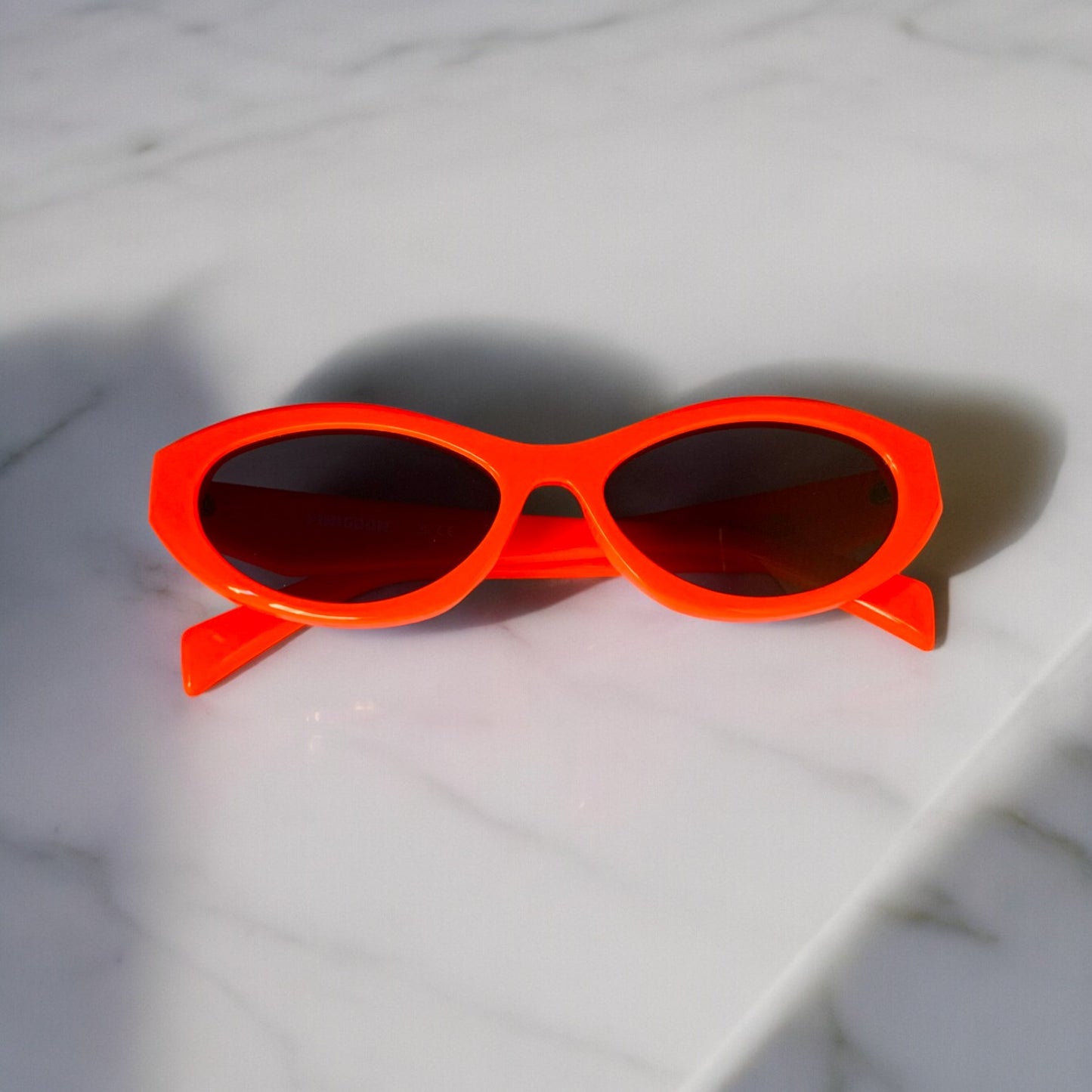 LUNETTES DE SOLEIL PINIGOON - LA NUMERO 19 ORANGE  OUVERTES SUR FOND MARBRE