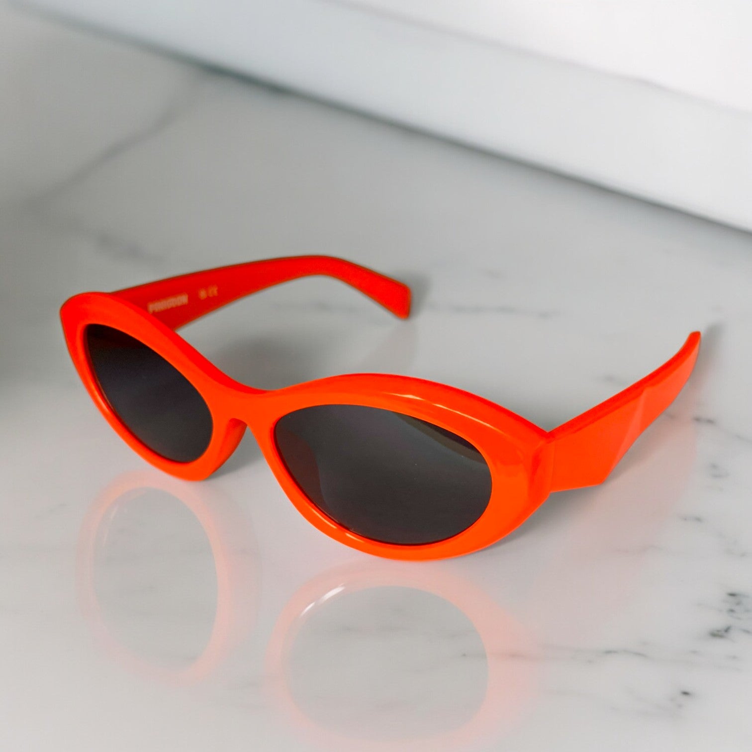 LUNETTES DE SOLEIL PINIGOON - LA NUMERO 19 ORANGE OUVERTES SUR FOND MARBRE OUVERTES