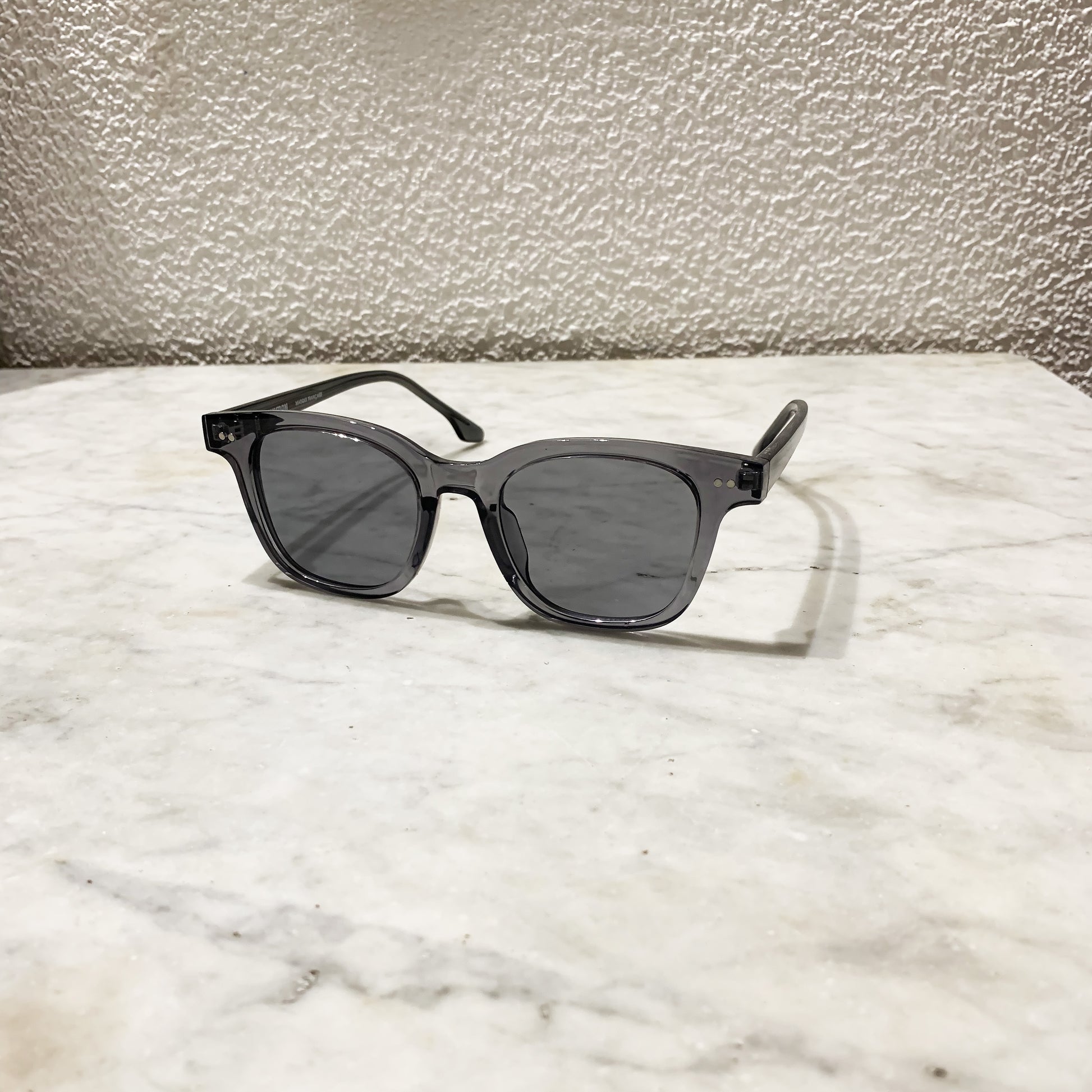 lunettes de soleil pinigoon grises ouvertes sur comptoir en marbre