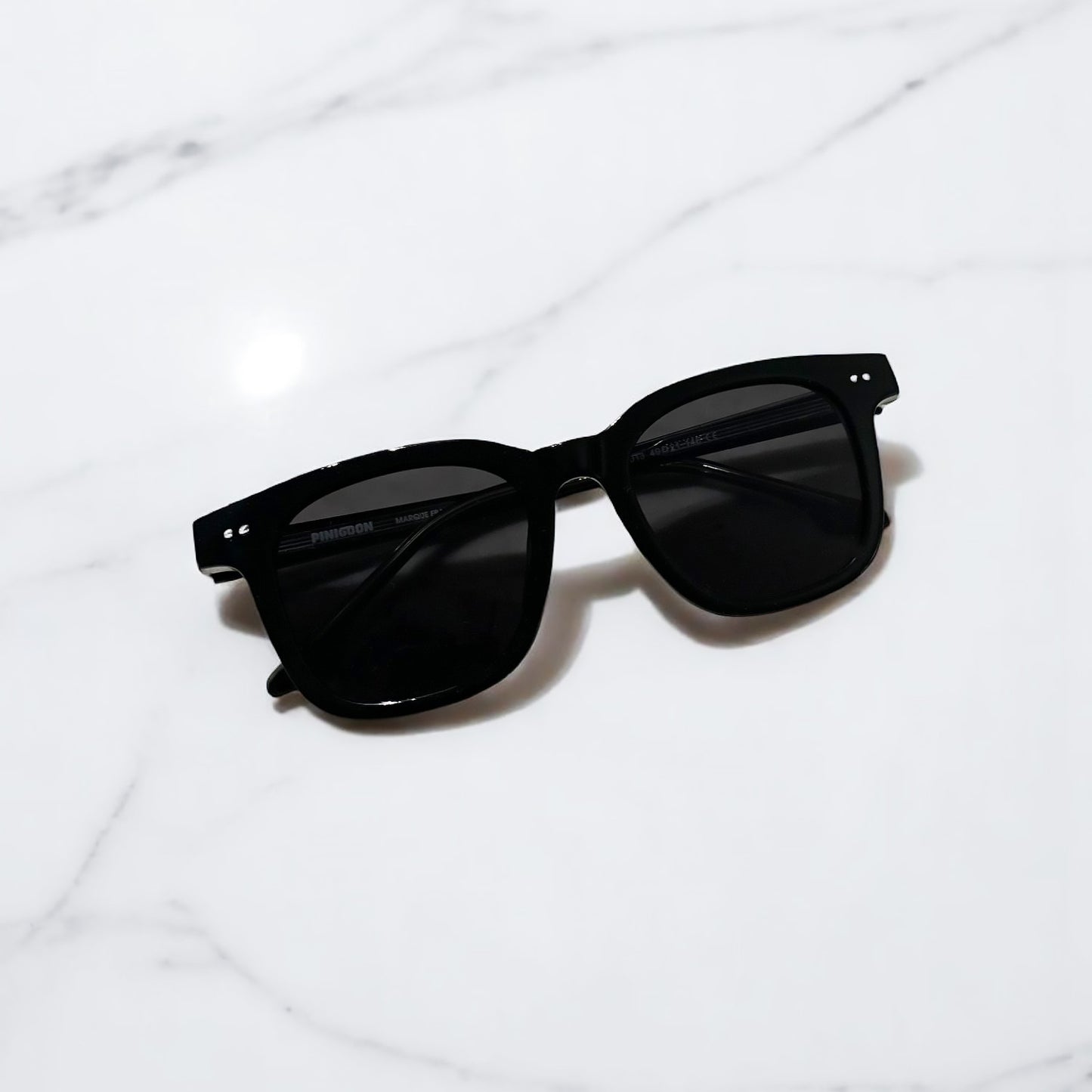 lunettes de soleil pinigoon noir fermées posées sur comptoir en marbre