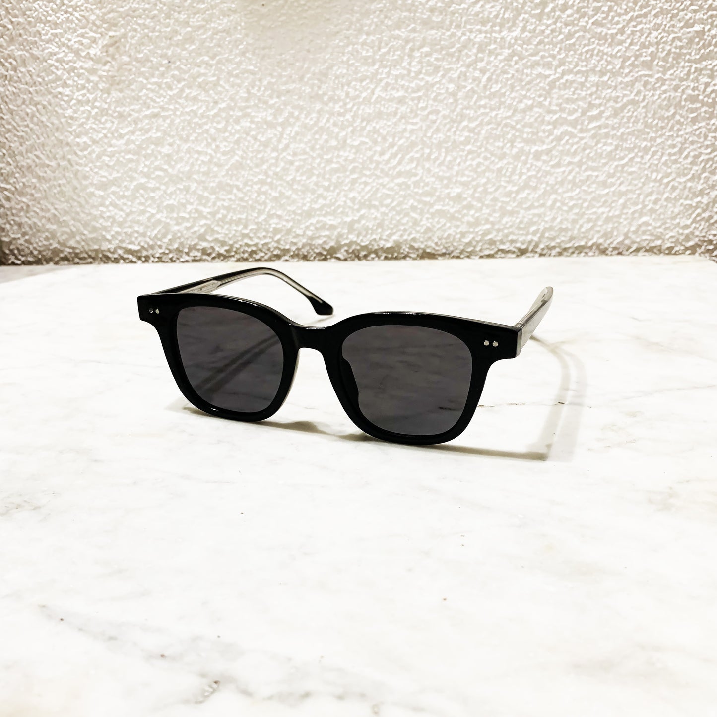 Lunettes de soleil Pinigoon noires posées sur comptoir en marbre