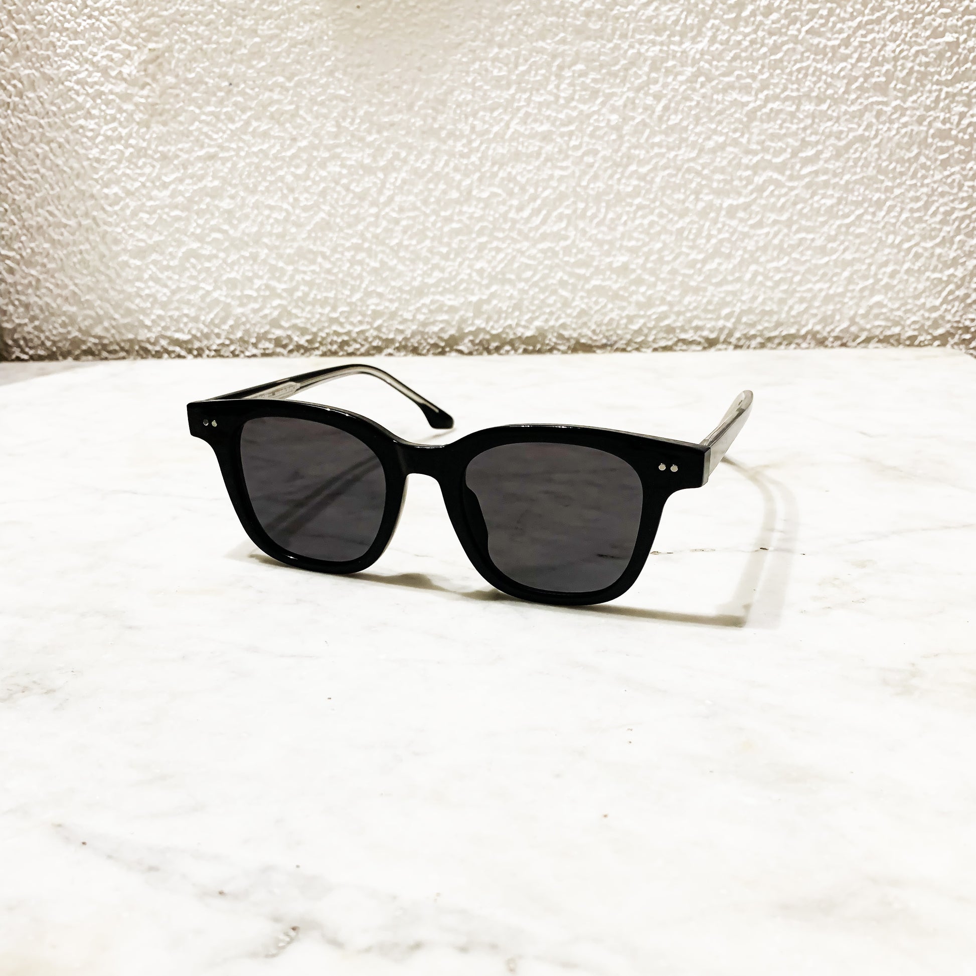 Lunettes de soleil Pinigoon noires posées sur comptoir en marbre