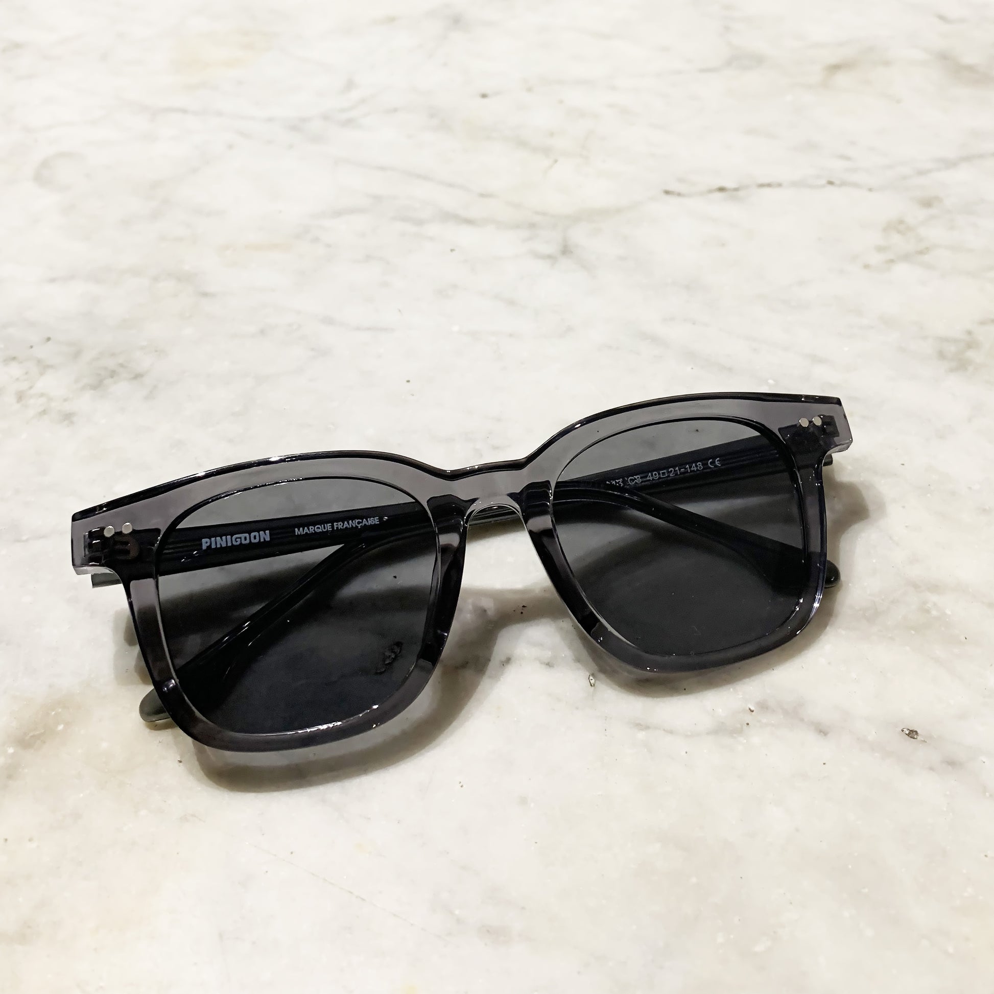 Lunettes de soleil grises Pinigoon posées sur comptoir e mrabre